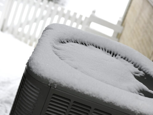 A snow-covered, frozen heat pump